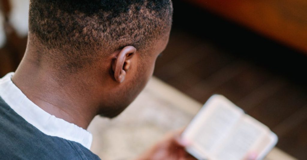 A man is deeply focused while reading a bible in a tranquil indoor setting, capturing a moment of faith.